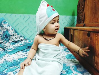 Girl looking away while sitting on bed