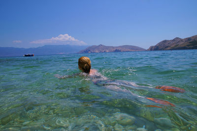 Man swimming in sea against blue sky