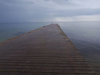 Wooden pier over sea against sky