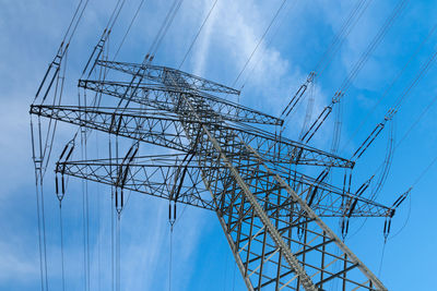 High voltage mast in front of blue sky with white clouds