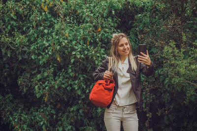 Portrait of young woman standing against plants