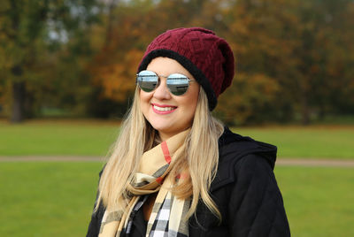 Portrait of smiling young woman wearing sunglasses while standing outdoors