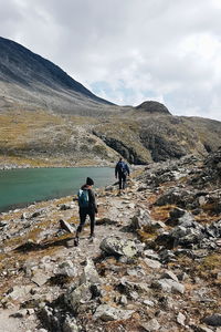 Rear view of people walking on rocks by lake