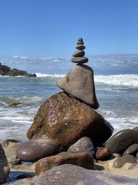 Stack of stones on beach against sky