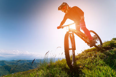 Rear view of man riding bicycle on mountain against sky