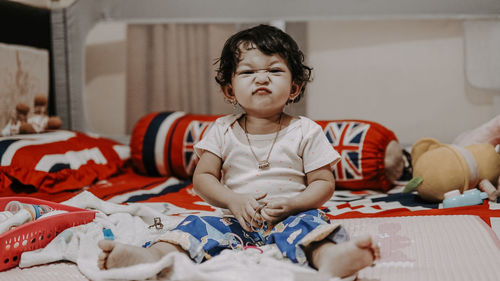 Portrait of cute girl sitting on bed at home