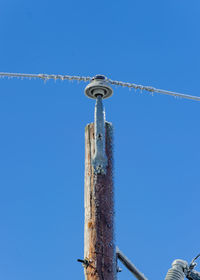 Low angle view of frosted power line against clear blue sky