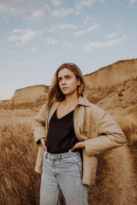 Portrait of beautiful young woman standing on land against sky