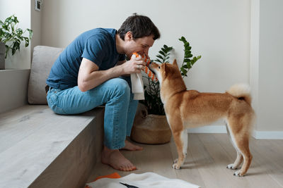 Funny adult man playing with a homemade dog toy with his favorite furry dog friend