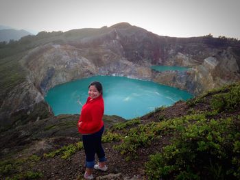 Portrait of woman standing on mountain against lake