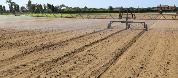 Industrial automatic irrigation system on the wide cultivated field with green lettuce in summer