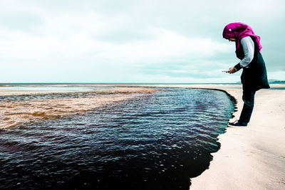 Woman standing on beach against sky