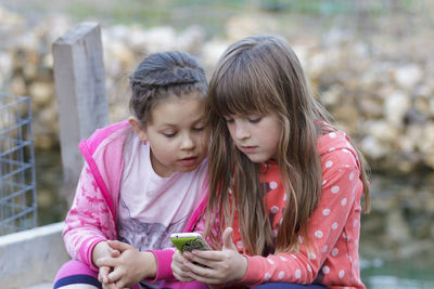 Girl and woman using mobile phone outdoors