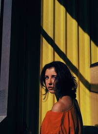 Portrait of young woman standing by wall