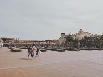 People walking on bridge against sky in city