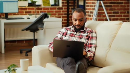 Young woman using digital tablet while sitting on sofa at home