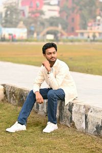 Young man using mobile phone while sitting on field