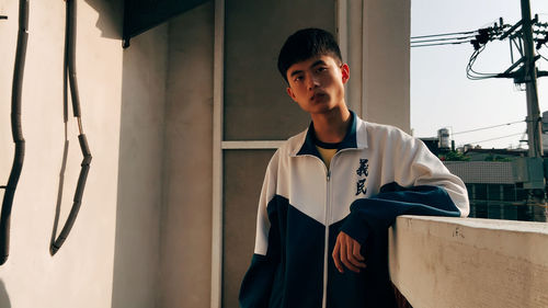 Portrait of young man standing against wall