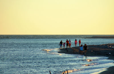 People at beach against clear sky
