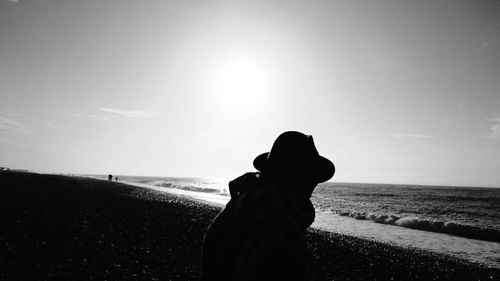 Silhouette person at beach against sky