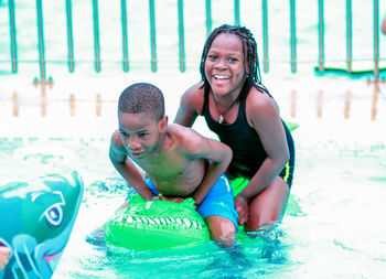 Portrait of smiling girl with boy on inflatable ring at swimming pool