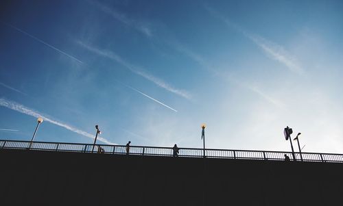 Low angle view of silhouette people on bridge against sky