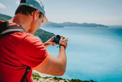 Rear view of man photographing sea against sky