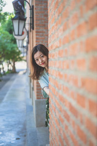 Portrait of smiling young woman standing against wall