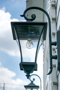 Low angle view of electric lamp against sky