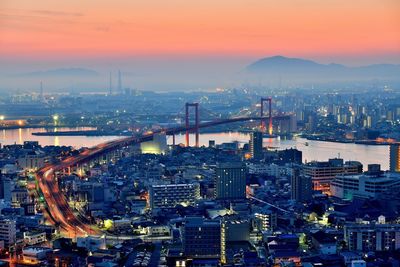 High angle view of illuminated city buildings against sky during sunset