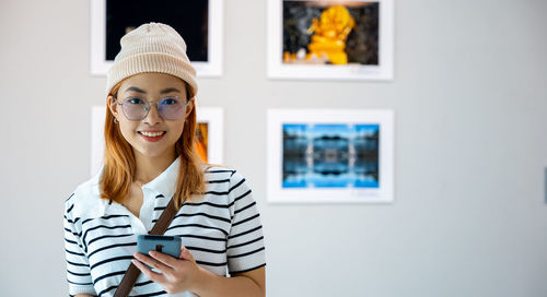 Portrait of young woman standing against wall