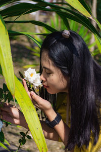Woman smelling white rose outdoors