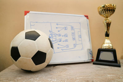 Close-up of soccer ball with award and whiteboard on table