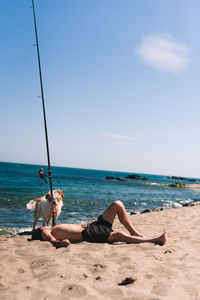 Woman relaxing on beach against sky