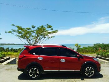 Red car on road against blue sky