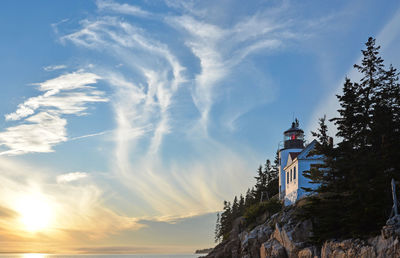 Low angle view of lighthouse by building against sky