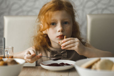 Redhead girl having breakfast at home