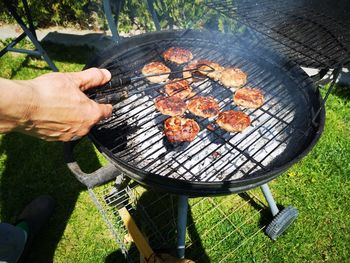 Men's hand making meatballs on barbecue.