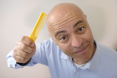 Close-up portrait of smiling bald man holding comb