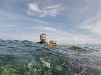 Portrait of young man swimming in sea against sky