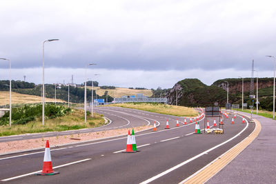 Vehicles on road against cloudy sky