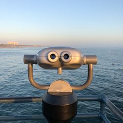 Close-up of coin-operated binoculars by sea against clear sky