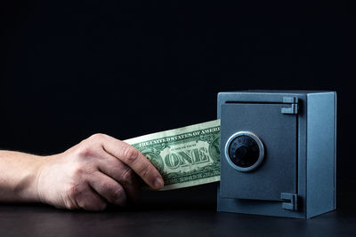 Close-up of hand holding camera over black background