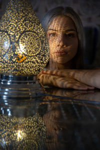 Portrait of woman by illuminated lamp on table