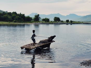 Man on boat in lake against sky