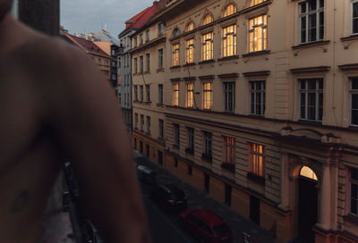 Midsection of man standing by building at dusk