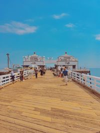 People on pier at beach against sky