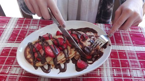 Close-up of hand holding ice cream in plate on table