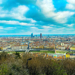 High angle view of city buildings against cloudy sky