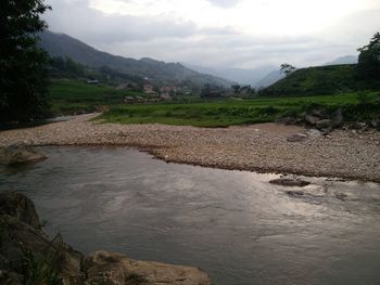 Scenic view of river by mountains against sky